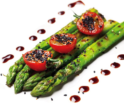 4 Mary Washington asparagus spears aside one another, seasoned with 3 halved cherry tomatoes on top with a dark sauce dotted alongside the asparagus