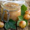 a jar of Gooseberry preserves and a few loose gooseberries on a wooden surface