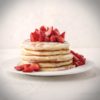 Stack of pancakes with strawberries and powdered sugar
